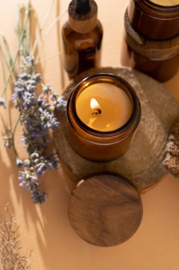Soy candles in a glass jar. Aromatherapy. Burning candle and lavender. Wooden lid for jars. Beige background. Comfort and relaxation. Handmade. Home decor.