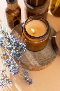 Soy candles in a glass jar. Aromatherapy. Burning candle and lavender. Wooden lid for jars. Beige background. Comfort and relaxation. Handmade. Home decor.