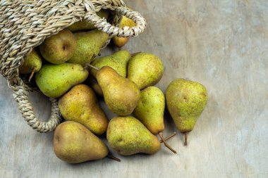 Ahşap bir arka planda sepetteki armutlar. Meyve hasadı. Sonbahar hala hayattır. Armut çeşitliliğinde Bera Konferansı. Vitamin yiyeceği..