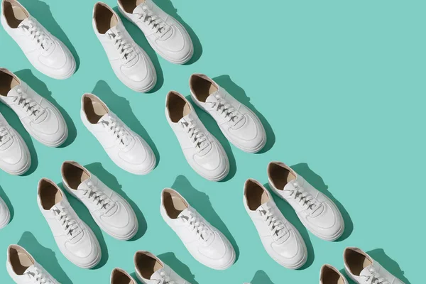 ミントブルーの背景にホワイトのスニーカーパターン 靴は快適でカジュアルなものです 靴屋の背景 新しいスニーカーの靴のペア — ストック写真