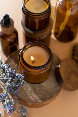 Soy candles in a glass jar. Aromatherapy. Burning candle and lavender. Wooden lid for jars. Beige background. Comfort and relaxation. Handmade. Home decor.