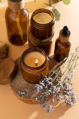 Soy candles in a glass jar. Aromatherapy. Burning candle and lavender. Wooden lid for jars. Beige background. Comfort and relaxation. Handmade. Home decor.