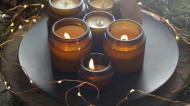 Soya mumları cam kavanozlarda yanar. Evdeki rahatlık. Kahverengi kavanozdaki mum. Koku ve ışık. Kokulu el yapımı mum. Aroma terapisi. Noel ağacı ve kış havası. Sıcak ev dekorasyonu. Şenlikli dekorasyon.