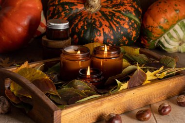 Soya mumları cam kavanozlarda yanar. Ağaç yaprakları, balkabağım. Evdeki rahatlık. Kahverengi kavanozdaki mum. Koku ve ışık. Kokulu el yapımı mum. Aroma terapisi. Sonbahar havası. Sonbaharda rahat ev dekorasyonu.