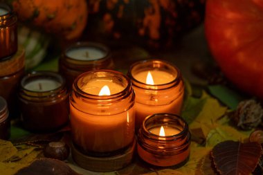 Soya mumları cam kavanozlarda yanar. Ağaç yaprakları, balkabağım. Evdeki rahatlık. Kahverengi kavanozdaki mum. Koku ve ışık. Kokulu el yapımı mum. Aroma terapisi. Sonbahar havası. Sonbaharda rahat ev dekorasyonu.