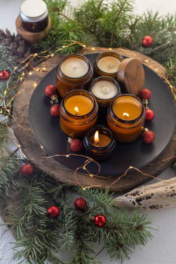 Soya mumları cam kavanozlarda yanar. Evdeki rahatlık. Kahverengi kavanozdaki mum. Koku ve ışık. Kokulu el yapımı mum. Aroma terapisi. Noel ağacı ve kış havası. Hoş bir dekor. Şenlikli çelenk dekorasyonu