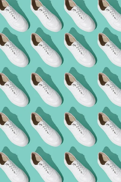 ミントブルーの背景にホワイトのスニーカーパターン 靴は快適でカジュアルなものです 靴屋の背景 新しいスニーカーの靴のペア — ストック写真