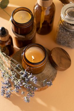 Soy candles in a glass jar. Aromatherapy. Burning candle and lavender. Wooden lid for jars. Beige background. Comfort and relaxation. Handmade. Home decor.