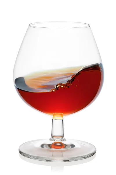 Splash van cognac in borrel glas. — Stockfoto