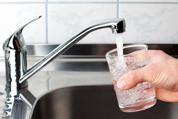 Glass filled with drinking water from kitchen faucet. — Stock Photo, Image