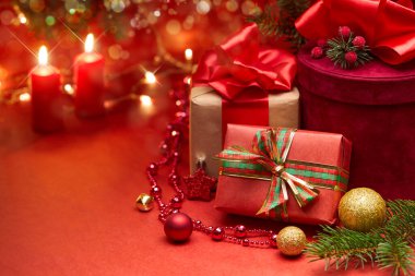 Kırmızı arka planda Noel hediye kutuları ve mumlar
