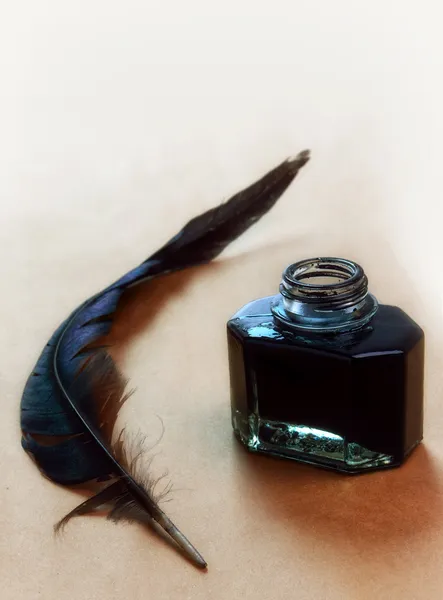 Feather and ink bottle on brown paper — Stock Photo, Image