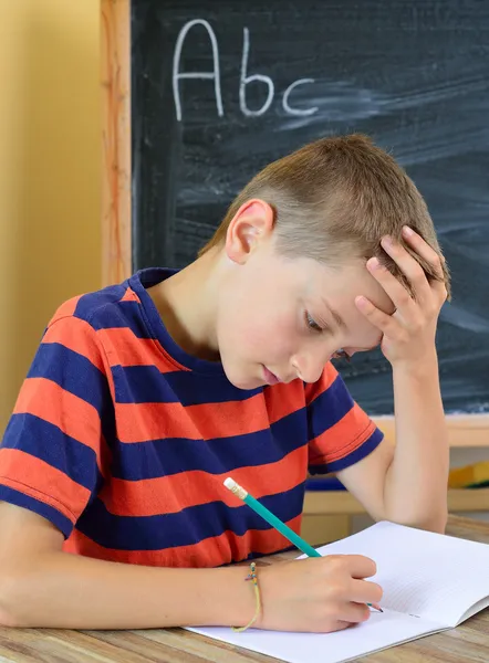 Jonge jongen probeert om zijn huiswerk te doen — Stockfoto