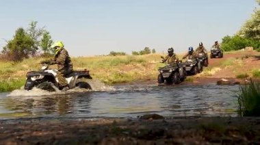 ATV 'li adamlar büyük bir vadiyi ve büyük bir nehri geçiyor.
