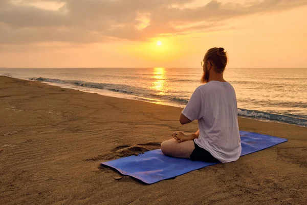 Man sits in lotus position at beach — Stock Photo, Image