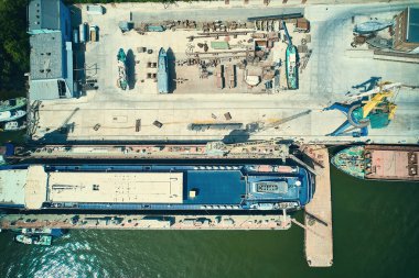 Aerial view of ship repair yard. Bulk carrier on a maintenance at dry dock and crane top down aerial view. River shipyard. 