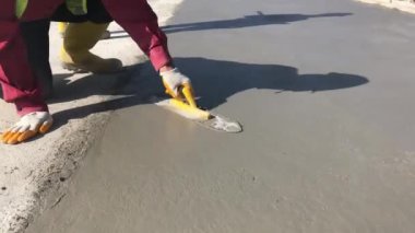 Construction worker uses trowel to level cement mortar screed. Concrete works on construction site. Cast-in-place work using trowels