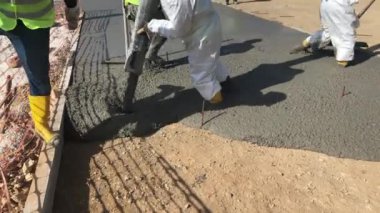 Üniforma giymiş inşaat işçileri formalite icabı beton döküyorlar. Çimento inşaat alanında çalışıyor.