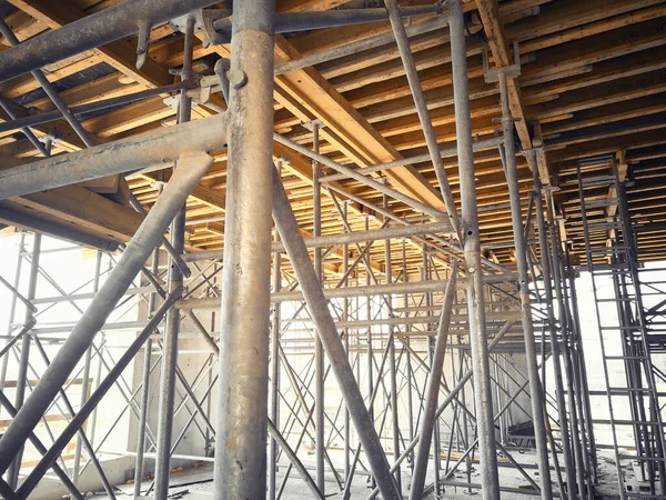 Framework of metal scaffolding support yellow formwork beams of floor slab. Supporting structures at construction site. Cast-in-place concrete works