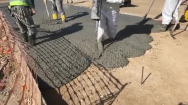 Üniforma giymiş inşaat işçileri formalite icabı beton döküyorlar. Çimento inşaat alanında çalışıyor.