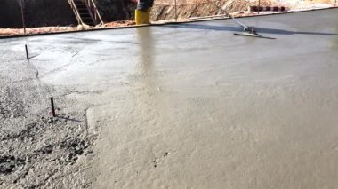 Construction worker uses trowel to level cement mortar screed. Concrete works on construction site. Cast-in-place work using trowels