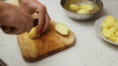Erkek eli kesme tahtasıyla patates keserken yakın plan. Ev işleri yapan bir adam. Bekar adam evde yemek pişiriyor.