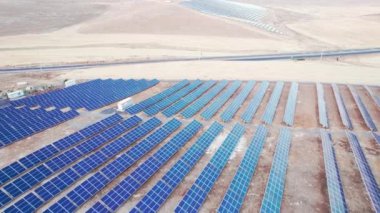 Güneş enerjisi istasyonu hava görüntüsü. Çöldeki güneş paneli çiftliğinin ve otoyolun havadan görünüşü. Solar fotovoltaik paneller. PV modül çiftliği. Güneş enerjisi çiftliği yüksek açılı hava görüntüsü