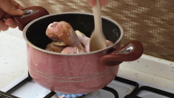 男性手拿着木勺和鸡腿放在锅里煎的特写镜头 单身汉煮鸡腿 男人做家务活 — 图库视频影像