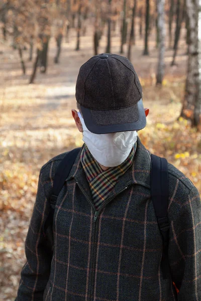 Insulation in the forest. A man in a cap and a white medical mask stands in a spring fores
