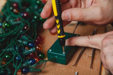 Yeni yıla hazırlanıyorduk. Noel ağacı elektrik çelengi tamiri. Eller tornavidayla kontrol kutusunu açar.