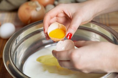 Kadın eli, yay üzerinde yumurta sarısı olan bir tavuk yumurtası kabuğunun yarısını tutar.