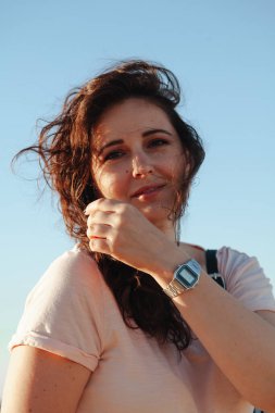 Uzun kızıl saçlı, mavi gökyüzüne karşı parlak sarı ceketli, iri yarı, güzel bir kızın portresi.