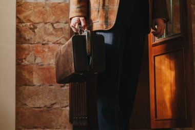 Şık bir ceketi olan beyefendinin elinde bir vintage ve bir ba...