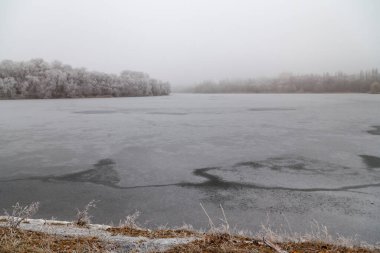 Donmuş bir nehirde çatlak. Nehrin yüzeyi buzla kaplı. Buzda büyük bir çatlak var. İç kısmın üstündeki gri sis