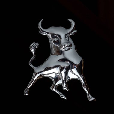 Chromed bull with large horns on a black background. The tail is raised hig