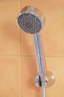 Chrome plated metal shower head mounted on tile wal