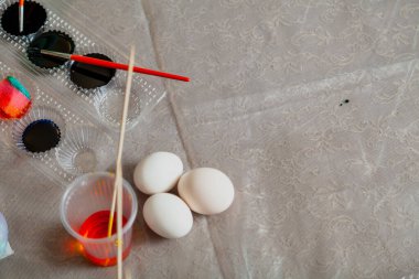 Paskalya yumurtalarının ev yapımı boyaları için besin kalitesinde boyalarla dolu plastik kaplar. Eldivenli eller yumurta boyamaya başladı bile.