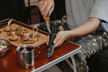 Toplanan mantarların incelenmesi. Tahta bir yaban domuzunun üstünde yenebilir mantar kesen bir adamın elleri.