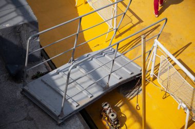 Sarı yüzen platformun üzerinde metal tırabzanları olan gri ahşap bir merdiven duruyor. Yukarıdan Görünüm