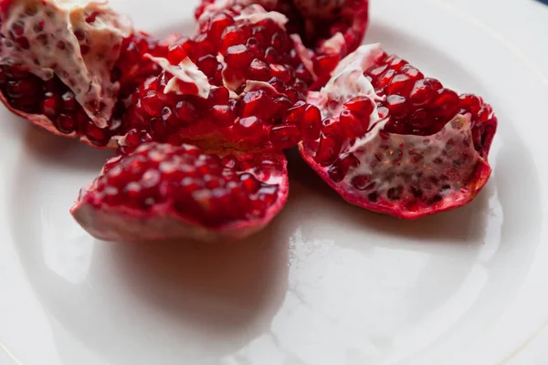 broken pomegranate with ripe red grains lies in a white bow