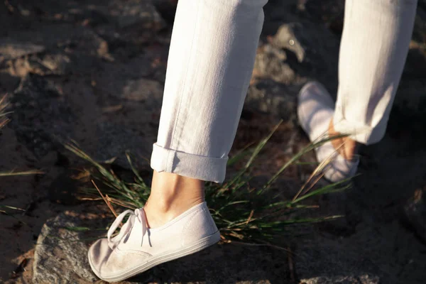 沿着海滩散步 在靠近你的沙滩上 穿着白色长裤和鞋子的女人的腿在石头上穿行 — 图库照片