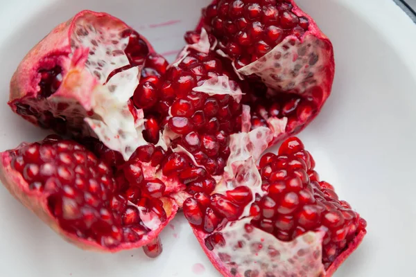 broken pomegranate with ripe red grains lies in a white bow