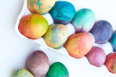 Paskalya tatiline özen göster. Farklı renklerde boyanmış birkaç tavuk yumurtası hücreli plastik bir kapta bulunur. Yakınlarda üç yumurta var.