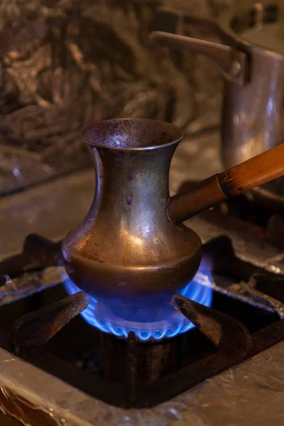 We make coffee over an open fire. Close-up of a brass Turk stands on a gas stove. A beautiful blue flame burns underneat