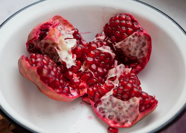 broken pomegranate with ripe red grains lies in a white bow