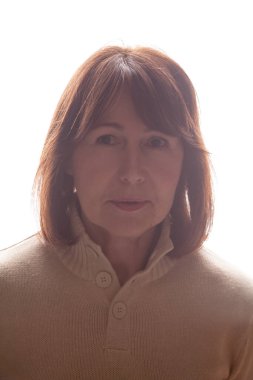 Beyaz bir arkaplanda rötuşsuz bir kadın portresi. Bej rengi terli, yaşlı, güzel bir kadın.