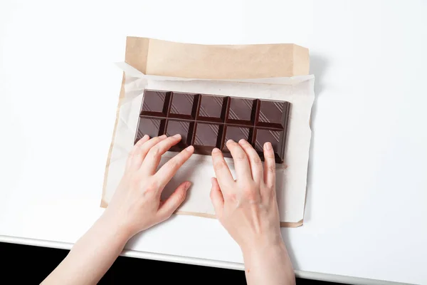 Hands rest on a large bar of dark chocolate. A comical comparison of a laptop keyboard with a bar of chocolate. Addiction to social networks and compute
