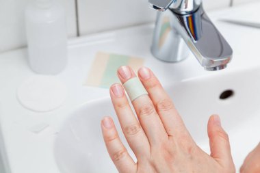 Prevention of minor hand injuries. A thin strip of a bactericidal plaster was applied to the middle finger of the left female hand. Close-u