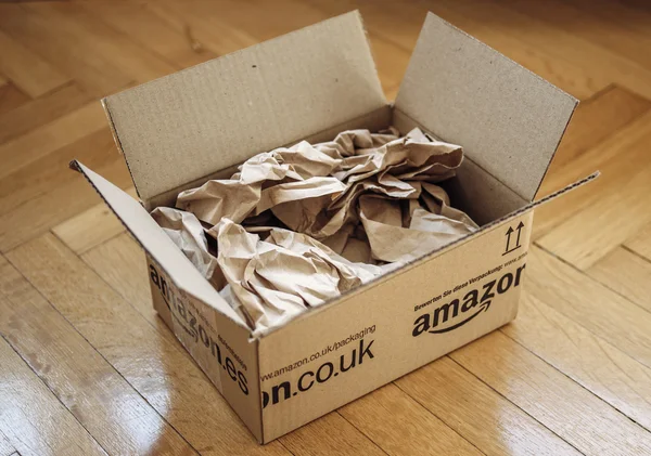 Opened parcel from Amazon on home parquet floor — Stock Photo, Image