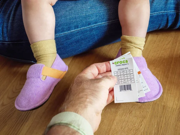 Ανδρική ετικέτα χέρι κρατώντας τιμή και το μέγεθος της ετικέτας Crocs παπούτσια για μωρά — Φωτογραφία Αρχείου